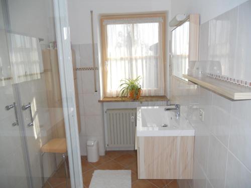 a white bathroom with a sink and a window at Ferienwohnung Edmeier in Bernau am Chiemsee