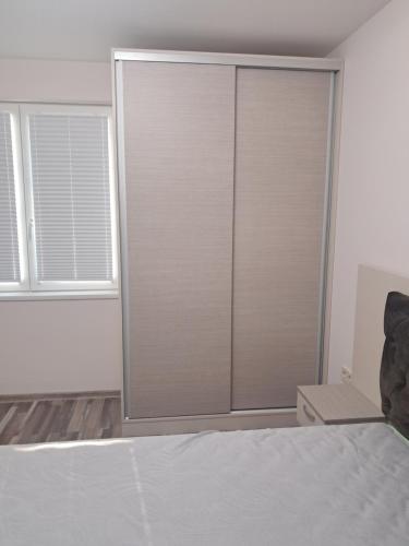a bedroom with a sliding closet door and two windows at Apartment Petrovi in Lovech