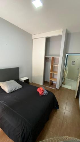 a bedroom with a black bed with a red hat on it at PB-Súper dpto Morón centro in Morón