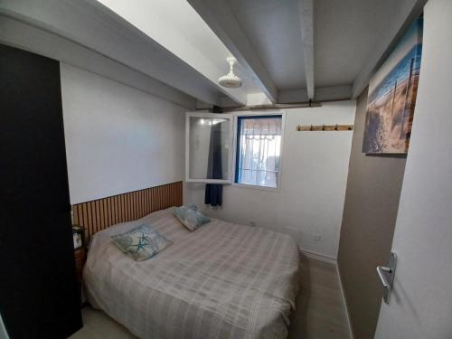 a small bedroom with a bed and a window at maison 100 m de la plage à pieds in Portiragnes