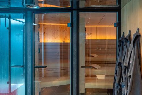 a glass door in a closet with wooden cabinets at Quality Hosts Arlberg - Hotel ANTON in Sankt Anton am Arlberg