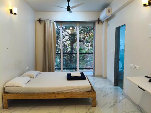a bedroom with a bed and a large window at Ecoark Farmstay in Cuncolim