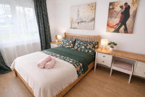 a bedroom with a bed with two pink slippers on it at Sutton Cosy Rooms in Sutton