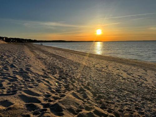 a beach with the sun setting over the water at Seabreeze #3 - Cozy cottage by the beach in Hampton Bays