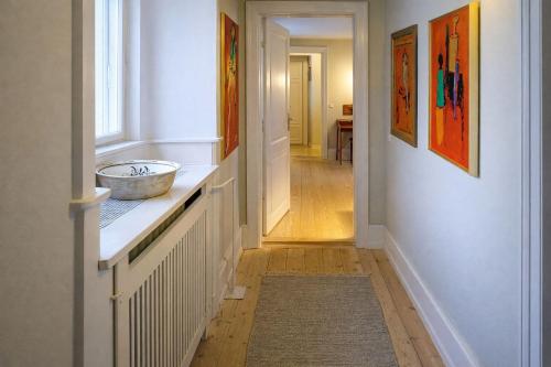 a hallway of a home with white walls and artwork at Holsteins Palace Luxury Apartment in Copenhagen