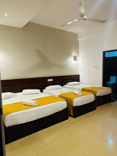 a room with three beds with yellow and white sheets at Hotel Divine Light Monaragala in Monaragala