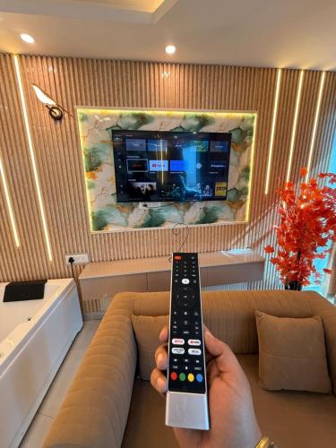 a person holding a remote control in front of a tv at Luxury Jacuzzi Studio -Couple Friendly- Noida in Ghaziabad