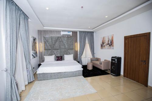 a bedroom with a white bed and a chair and a window at The Kitchen Kabinet in Abuja
