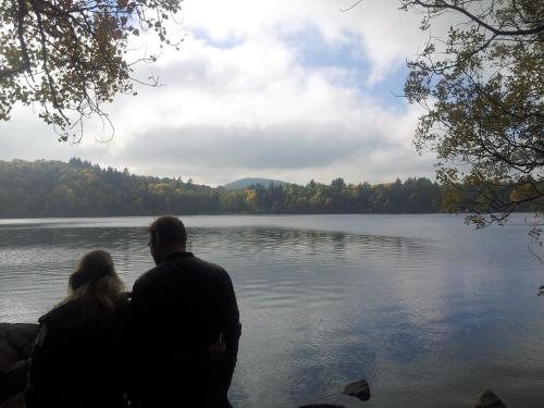 a man and a woman sitting next to a lake at Moulin de la Fayolle in Blot-lʼÉglise