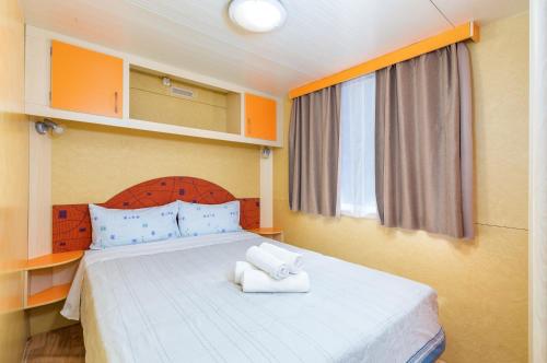 a bedroom with a bed with two towels on it at Arena Tasalera Mobile Homes in Premantura