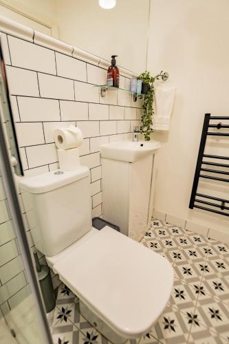 a white toilet in a bathroom with white tiles at Marina View Studio - Harbour in Dublin