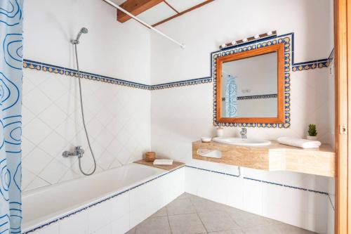 a bathroom with a tub and a sink and a mirror at Villa Maru II by Villa Plus in Cala en Porter