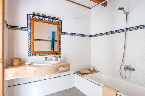a bathroom with a tub and a sink and a mirror at Villa Maru I by Villa Plus in Cala en Porter