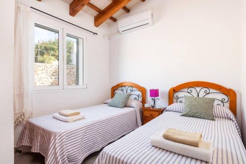 two beds in a room with two windows at Villa Maru I by Villa Plus in Cala en Porter