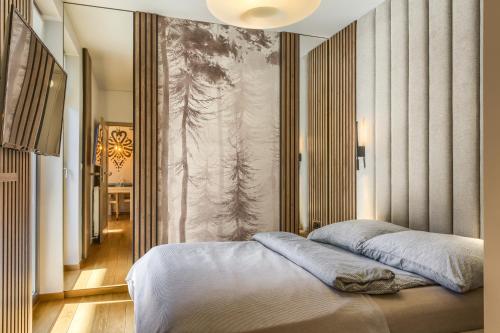 a bedroom with a bed and a wall with a painting at Tatry Top Apartamenty Granitica centrum in Zakopane