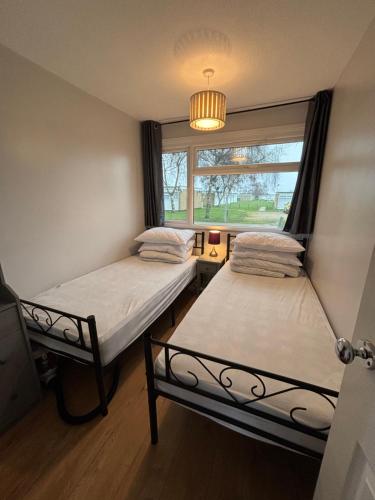 two beds in a room with a window at 194, Two bed Chalet on Belle Aire Holiday Park - sleeps 4, pet friendly, free Wi-Fi, bed linen and towels included plus onsite entertainment available in Hemsby