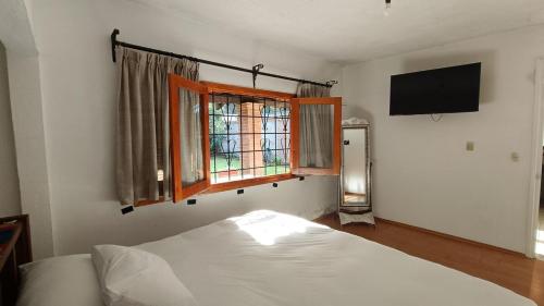 a bedroom with a bed and a window and a television at Popo Country House in Atlautla
