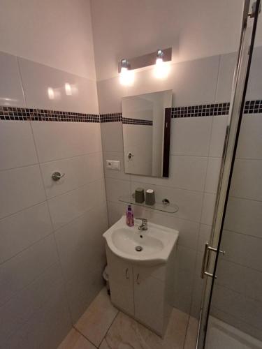 a white bathroom with a sink and a shower at Apartmány ARIES in Nitra