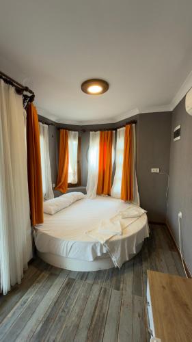 a bedroom with a large bed with orange curtains at Sarıyer Otel in Ula
