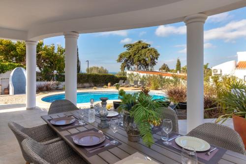 a patio with a table and chairs and a swimming pool at Villa Ocean Blue Ocean views Walk to beach Pool in Ferragudo