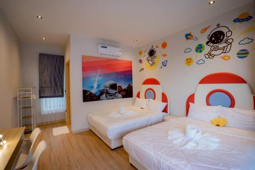 a bedroom with two beds and a painting on the wall at CC POOL VILLA พลูวิลล่าcha-am in Cha Am