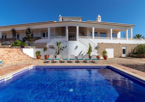 a villa with a swimming pool in front of a house at Villa Atlantic Blue Luxury with Ocean views in Ferragudo