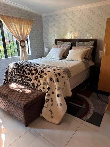 a bedroom with a bed with a leopard blanket and a bench at Cactus Village in Blantyre