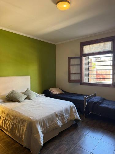 a bedroom with green walls and a bed and a window at Casa 2 hab, cerca del centro y costanera in Gualeguaychú