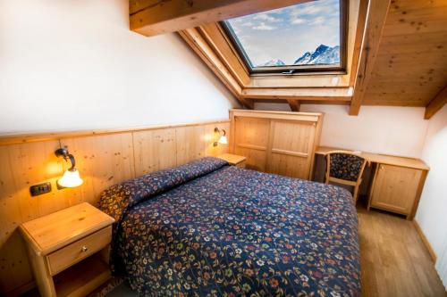 a bedroom with a bed and a large window at Hotel Giardino in Bormio