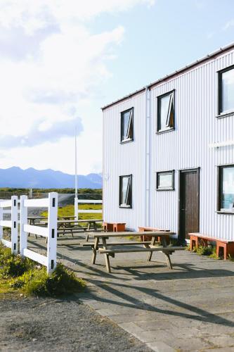 a group of picnic tables in front of a building at Eldborg Cabins and Guesthouse in Kolbeinsstaðir