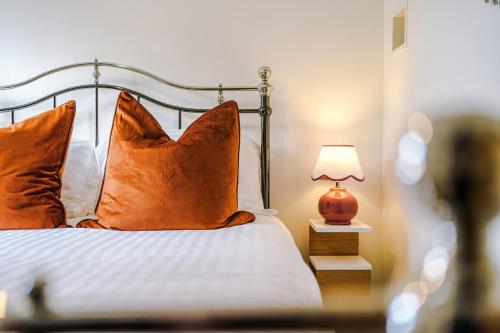 a bedroom with a bed with orange pillows and a lamp at Cosy Lake District Cottage - Walk to Windermere - Sleeps 6 in Windermere