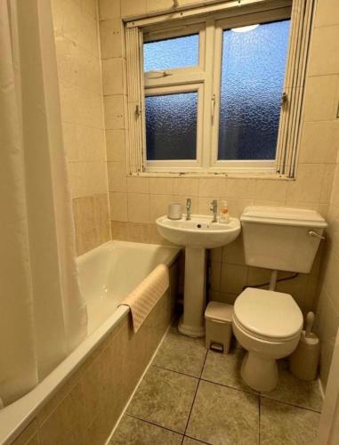 a bathroom with a toilet and a sink and a tub at Cosy Budget Rooms in Camden Town near Regents Park in London
