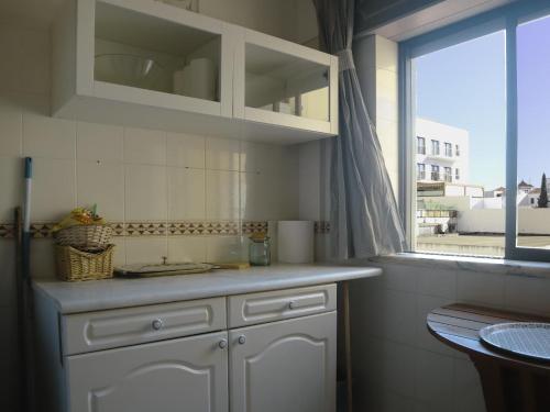 a kitchen with white cabinets and a window at Humen apartamento T2 in Tavira