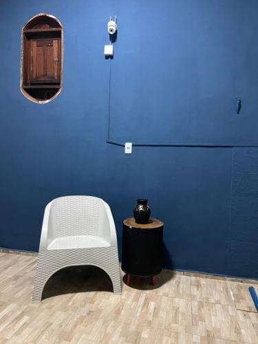 a blue wall with a white chair and a table at Pousada É de casa unidade 02 apto 01 in Juazeiro do Norte