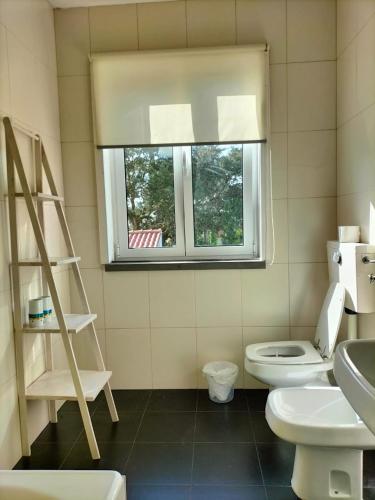 a bathroom with a white toilet and a window at Casa do Pinhal in Moledo
