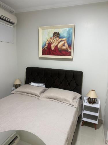 a bedroom with a bed with a painting on the wall at Apartamento de Denise in Aracaju