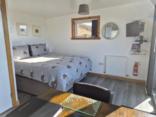 a bedroom with a bed and a table and a window at Lampay Chalets in Dunvegan