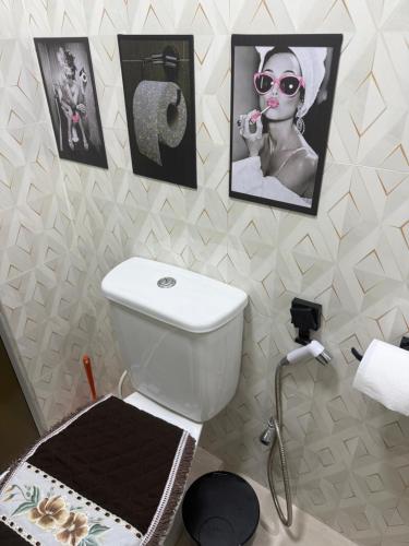 a bathroom with a toilet and pictures on the wall at Apartamento de Denise in Aracaju