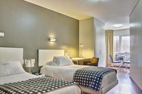 a hotel room with two beds and a desk at Regency Golf - Hotel Urbano in Montevideo