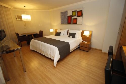 a hotel room with a large bed and a table at Actuall Convention Hotel in Contagem