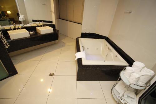 a bathroom with two sinks and a bath tub at Actuall Convention Hotel in Contagem