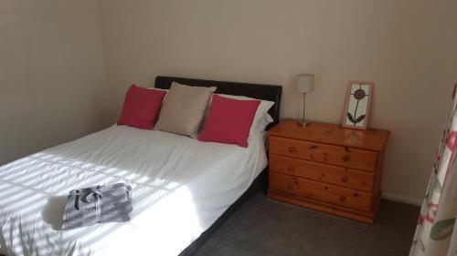 1 dormitorio con 1 cama con almohadas rosas y vestidor en Sea Glass Cottage en Sunderland