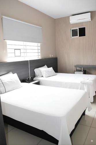 two beds in a hotel room with white sheets at Hotel Doral Inn in Ibagué