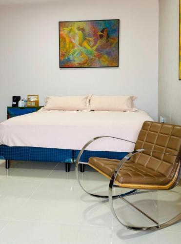 a bedroom with a bed and a chair at Kundera Hotel Boutique in Colima