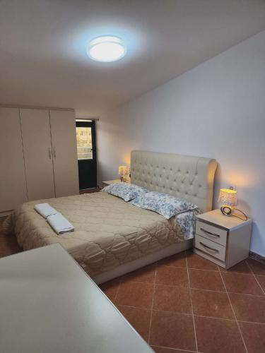 a bedroom with a large bed and a night stand at Apartment 3 by Villa Ceni in Elbasan