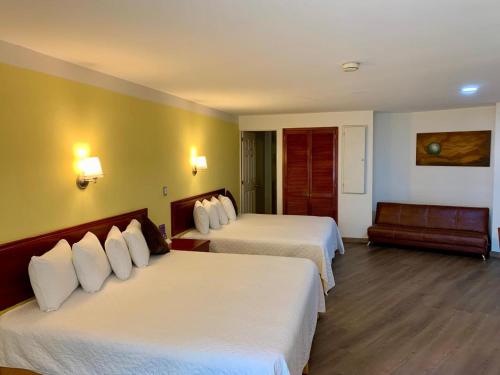 a hotel room with two beds and a couch at Hotel Enterprise Inn Poliforum in León