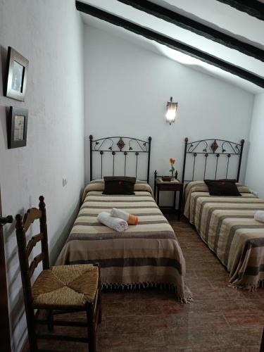 a room with two beds and a chair in it at Posada El Majuelo in Baños de la Encina