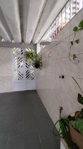 a hallway with white doors and potted plants at Casa Amarelinha da Tupi in Praia Grande
