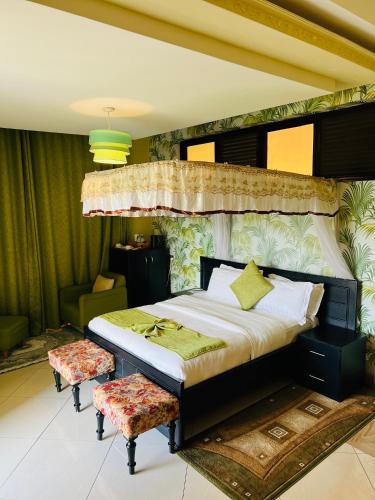 a bedroom with a large bed and two chairs at Las Vegas Garden Hotel-Kampala in Kampala