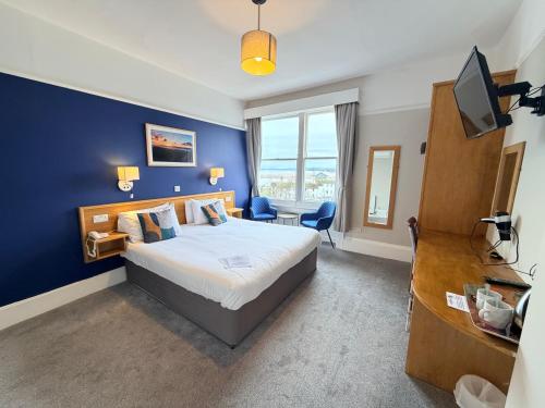 a bedroom with a bed and a blue wall at Manor Hotel in Exmouth